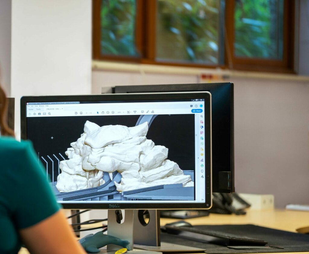 A woman using CAD software for 3D modeling in an office setting with a back view.